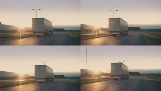 一辆带拖车的半卡车在高速公路上行驶的后续镜头。一辆白色卡车在阳光照耀下的空旷道路上穿过工业仓库。高清在线视频素材下载