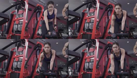 年轻的亚洲肌肉女性锻炼哑铃划船在健身房，生活方式运动和健美的概念高清在线视频素材下载