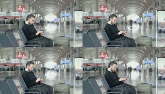乘客在机场候机室边听音乐边使用智能手机高清在线视频素材下载