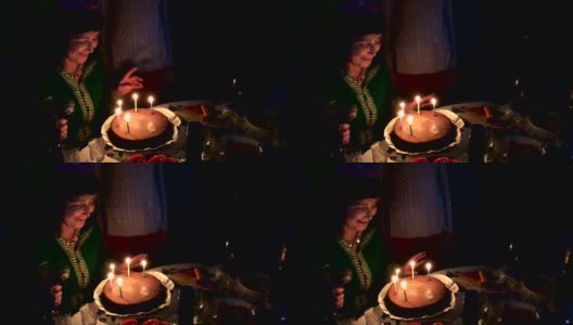 成熟的成年白人女性吹灭生日蛋糕上的蜡烛。高清在线视频素材下载