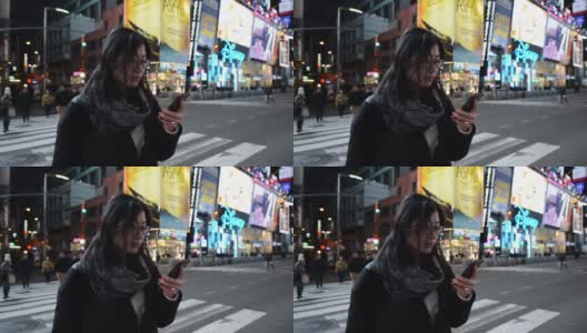 亚洲女性晚上在时代广场使用智能手机高清在线视频素材下载