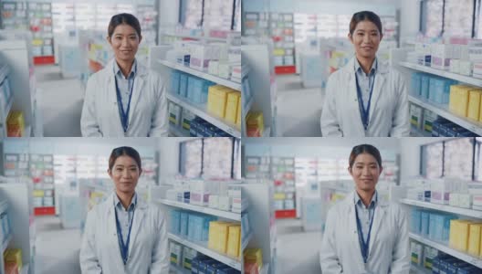 药店:美丽的亚洲药剂师的肖像穿着白大褂，看着相机和迷人的微笑，在她的摆满药包的货架后面。中等的特写镜头高清在线视频素材下载