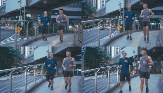 亚洲华人活跃的老人和儿子晚上下班后一起在城里跑步慢跑高清在线视频素材下载