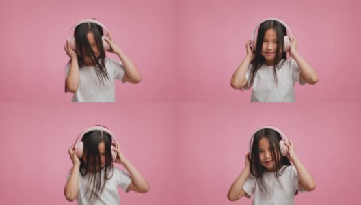 日本女孩戴着耳机听音乐跳舞在粉红色的背景高清在线视频素材下载