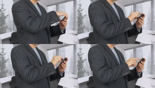 商人在冬天的办公室里用智能手机浏览度假照片高清在线视频素材下载