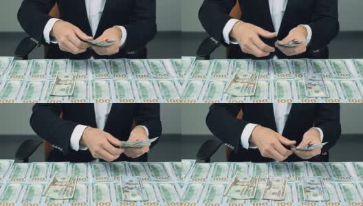 男人在数着很多美元。桌子上有很多100美元的钞票高清在线视频素材下载