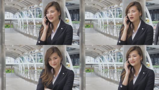 美丽的亚洲女商人手拿智能手机在外面的现代城市高清在线视频素材下载