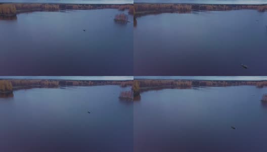飞过蓝色的湖，在秋天的森林里。龙利小船漂浮在荡漾的水面上高清在线视频素材下载