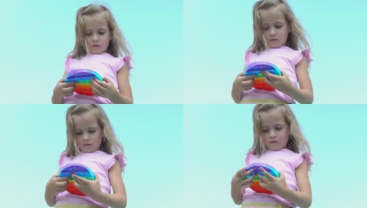 穿粉红色衣服的女孩扮演波普尔。孩子热衷于彩虹抗压力。孩子的硅胶玩具高清在线视频素材下载