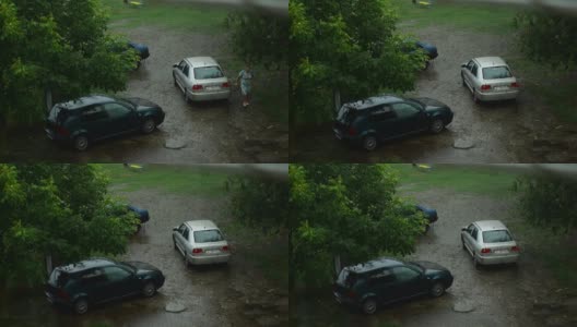 下雨了。女人下了车，走过水坑里的第二辆车。高清在线视频素材下载