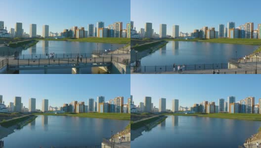 俄罗斯叶卡捷琳堡，一个池塘和一座新公园里的桥。视频。一个美丽的城市地区的鸟瞰图与五颜六色的高层建筑在蓝天的背景高清在线视频素材下载