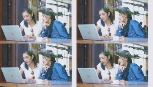 两个女朋友在咖啡馆用笔记本电脑分享咖啡。高清在线视频素材下载