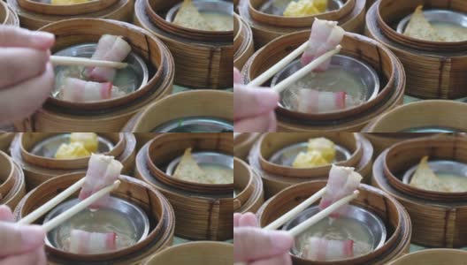 手用筷子吃传统的中国食物新鲜，美味，美味，美味的蒸肉点心在餐厅的竹篮高清在线视频素材下载