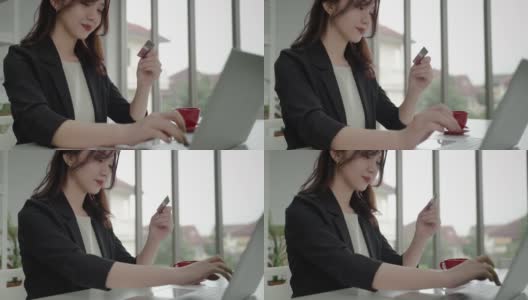 一位亚洲女商人正在用她的信用卡和笔记本电脑进行网上银行业务。技术和商业的概念高清在线视频素材下载