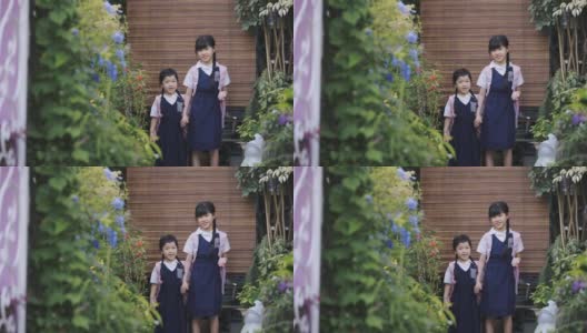 早上，亚洲的中国姐妹们手牵着手从家走到房子的前院上学高清在线视频素材下载