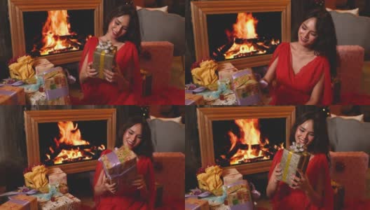 漂亮的女人在她的房子的壁炉前拿着许多圣诞礼品盒，看起来很开心高清在线视频素材下载