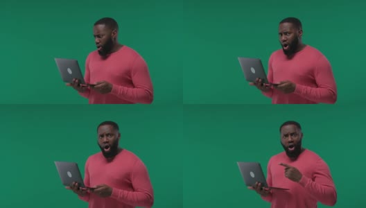 一个黑人惊喜地看到了他在绿色屏幕上的笔记本电脑，色度键高清在线视频素材下载