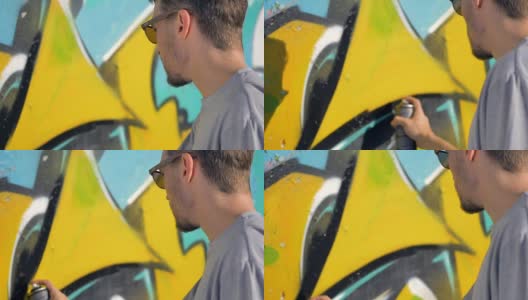 涂鸦艺术家正在墙上黄色字母附近画一条黑线。高清在线视频素材下载