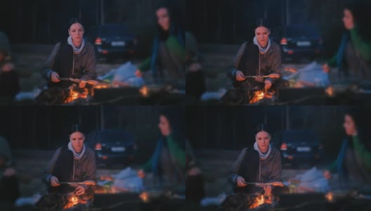 两个女人在火上煎香肠。晚上的家庭露营。高清在线视频素材下载
