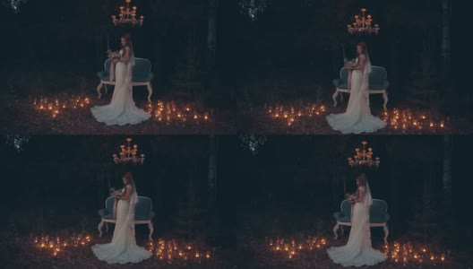 在漆黑的森林里，新娘手捧花束，站在沙发前，点燃蜡烛。高清在线视频素材下载