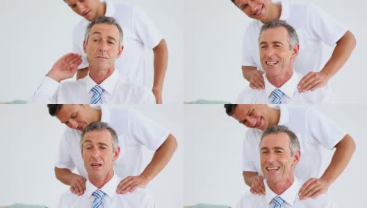 理疗师给紧张的商人做肩部按摩高清在线视频素材下载