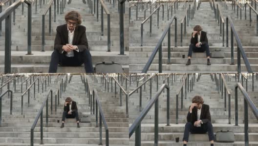 一个沮丧的商人坐在商业中心附近的楼梯上高清在线视频素材下载