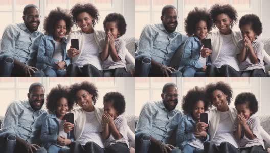 快乐的非洲父母和孩子们在沙发上用手机大笑高清在线视频素材下载