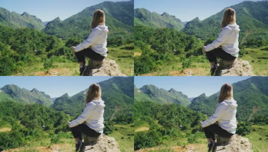 白种女游客坐在山顶的边缘，看自然和风景的山高清在线视频素材下载