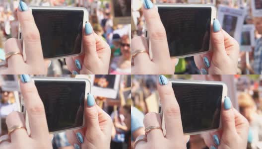 女孩的手在智能手机上取下的特写一大群人走在街上，慢镜头高清在线视频素材下载