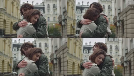 一对可爱的情侣在街上拥抱。快乐女友向户外男友倾斜。高清在线视频素材下载