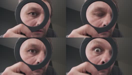 一个中年男人透过放大镜看照相机的眼睛。幽默的高清在线视频素材下载