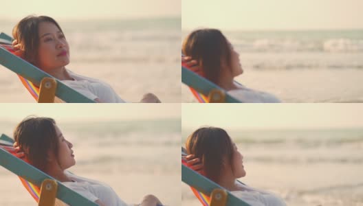 4K美丽的亚洲女人在日落时躺在海边的沙滩椅上高清在线视频素材下载