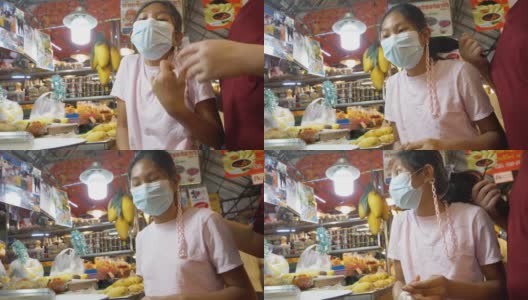 在泰国著名海鲜店华欣夜市买芒果糯米饭的亚洲孩子们戴着口罩。高清在线视频素材下载