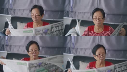 老妇人坐在沙发上看报纸。高清在线视频素材下载