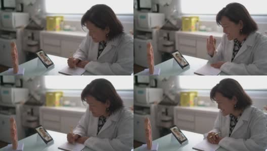 医生在一个远程医疗视频电话与老年患者使用移动电话在医疗诊所高清在线视频素材下载
