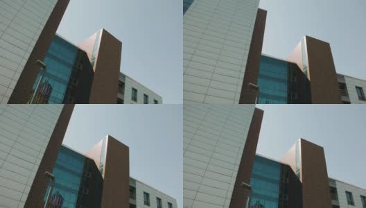 一座相当高的商业建筑，玻璃倒映着天空。在拍摄对象时，相机平稳地倾斜高清在线视频素材下载