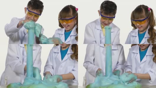 两个可爱的化学家孩子做有趣和成功的实验与蓝色泡沫，玩，得到快乐孤立在白色背景，慢镜头，近距离高清在线视频素材下载