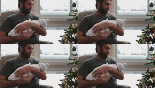 冬日里，慈爱的爸爸带着刚出生的宝宝靠近窗户高清在线视频素材下载