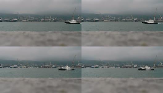 一艘巡逻艇驶过一个工业港口城市的海湾。高清在线视频素材下载