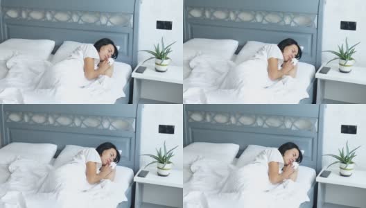 女人独自睡在一个大而舒适的床上，白色的亚麻布在下午在家里高清在线视频素材下载
