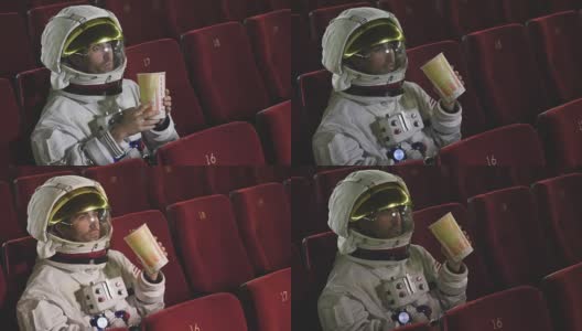 一名宇航员一边看电影一边吃着爆米花，享受着电影的乐趣。概念:电影和太空电影，电影的另一个世界，超现实的情况。高清在线视频素材下载