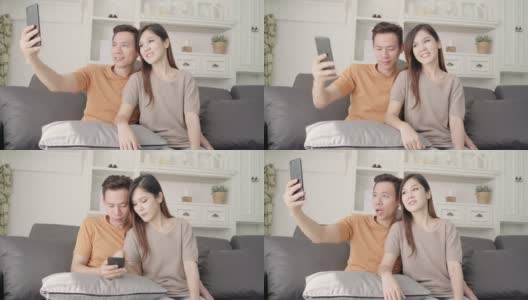 亚洲情侣在家客厅用智能手机自拍，甜蜜的情侣躺在沙发上放松享受爱情时刻。生活方式夫妇在家里放松的概念。高清在线视频素材下载