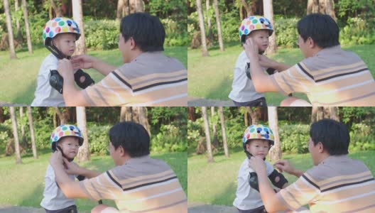 爸爸把头盔戴在亚洲2 - 3岁蹒跚学步的小男孩身上，爸爸和儿子玩平衡自行车高清在线视频素材下载