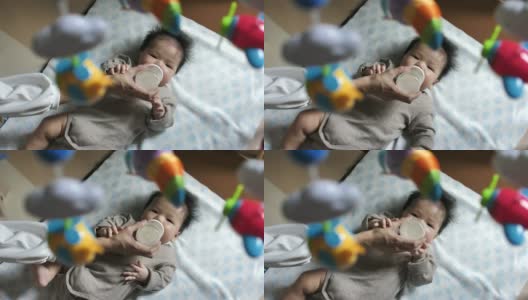 年轻的亚洲母亲在家用奶瓶喂男婴高清在线视频素材下载
