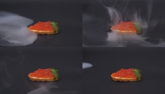 壮观的俄罗斯传统奢华假日小吃——用红鱼子酱装饰的欧芹叶三明治，烟雾缭绕，黑色背景高清在线视频素材下载