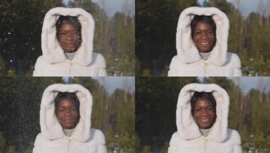 一位非裔美国妇女在闪闪发光的雪下摆姿势微笑高清在线视频素材下载