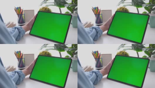 人工手握空白绿屏数码板站在家里的工作台上进行模拟，模板，技术概念高清在线视频素材下载