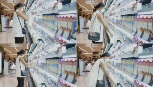 年轻的亚洲女性在超市的冷冻室里选择和挑选产品，戴上防护灰尘和病毒的面罩，保持健康。高清在线视频素材下载