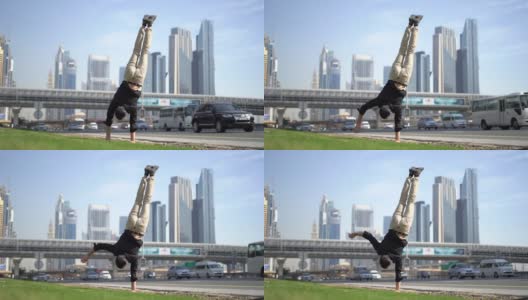 杂技演员一只手保持平衡，模糊的迪拜城市景观。现代健康生活理念。高清在线视频素材下载