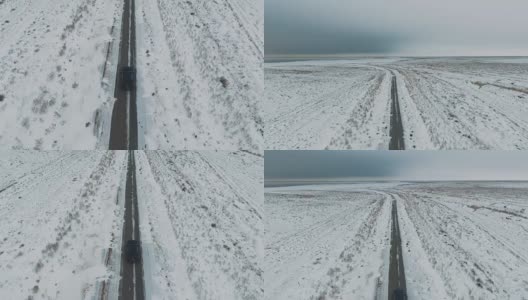 一辆黑色汽车行驶在雪地里的乡村道路上，无人机拍摄的鸟瞰图高清在线视频素材下载